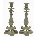 A pair of Regency bronze and gilt candlesticks,with removable drip pans, cast with stiff leaf