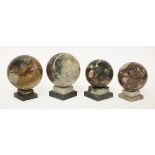 Four marble balls,on stepped plinths,15cm highest (4)