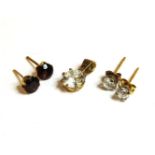A pair of gold garnet stud earrings, a pair of single stone diamond stud earrings, and a gold