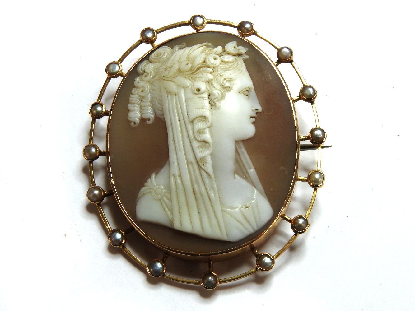 An Edwardian gold shell cameo brooch, of a young maiden, with garland to hair, the mount set with