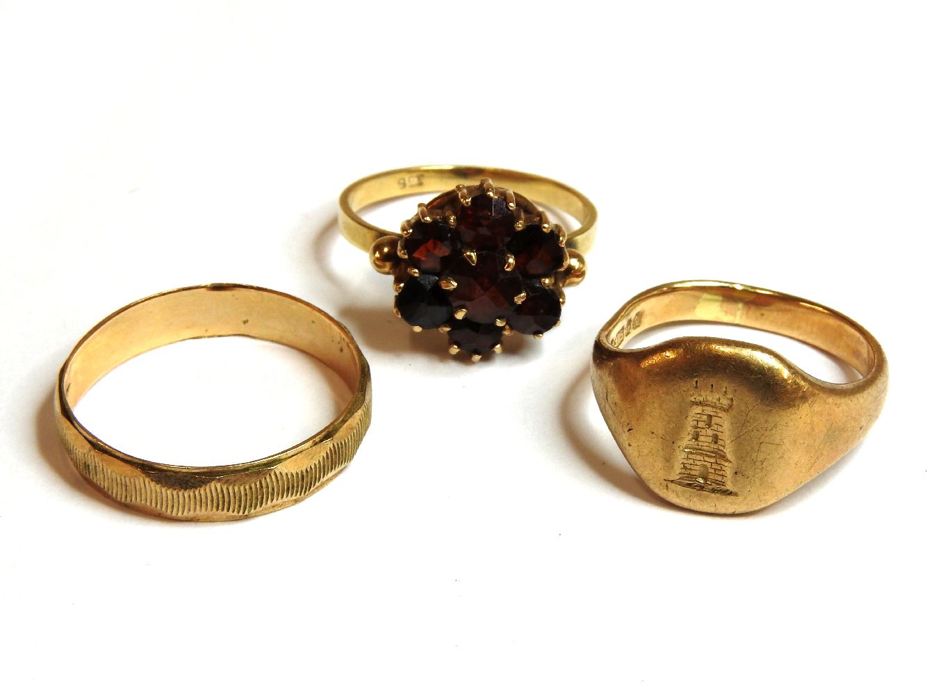 A 9ct gold wedding ring, a 9ct gold signet ring, and a gold garnet cluster ring, marked 9ct