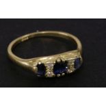 A three stone sapphire ring, set with four diamond points, marked 18ct, 3.02g