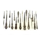 16 silver and mother of pearl handled button hooks, and 4 further items, in a glazed display case