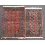 Two eastern rugs decorated with geometric designs on a red ground, approximately 185cm x 127cm and