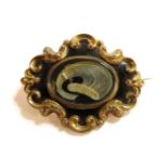 A gold cased black enamel memorial brooch, set with a lock of hair, with engraved inscription verso