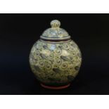 A Coxwold Pottery jar and cover, by Peter Dick, the tenmoku glaze decorated with fish motifs, 26cm