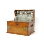 An Edwardian oak tantalus, with silver plated mounts, 3 cut glass decanters, 2 lift up flaps and a