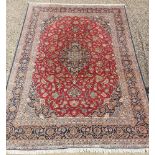 A hand knotted Persian Kashan carpet, the red fields with central turquoise pendant, with foliate