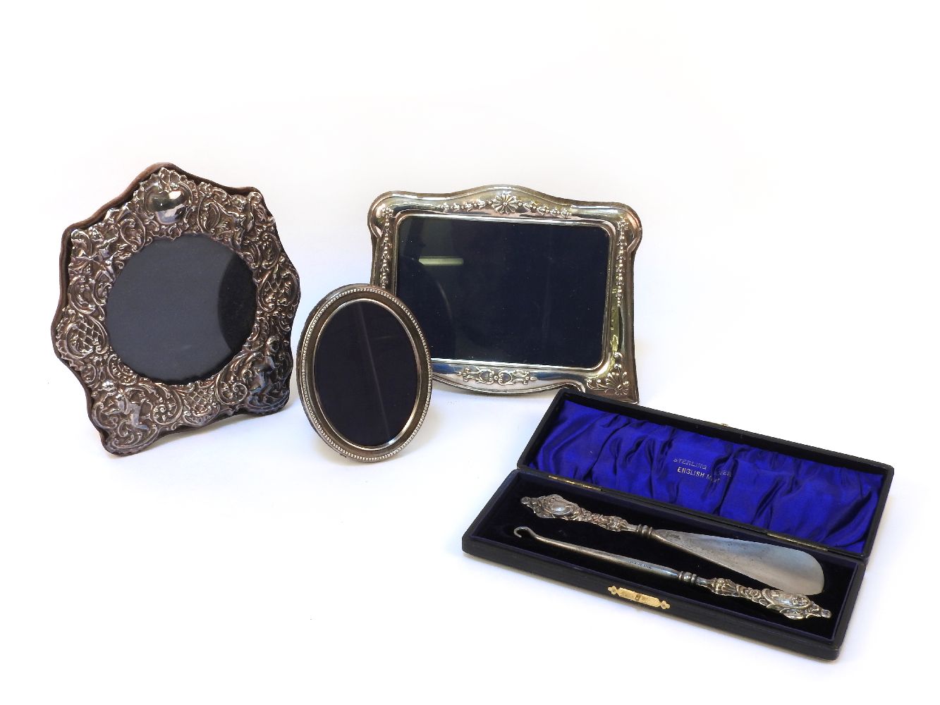 Three silver photo frames, together with a button hook, and shoe horn