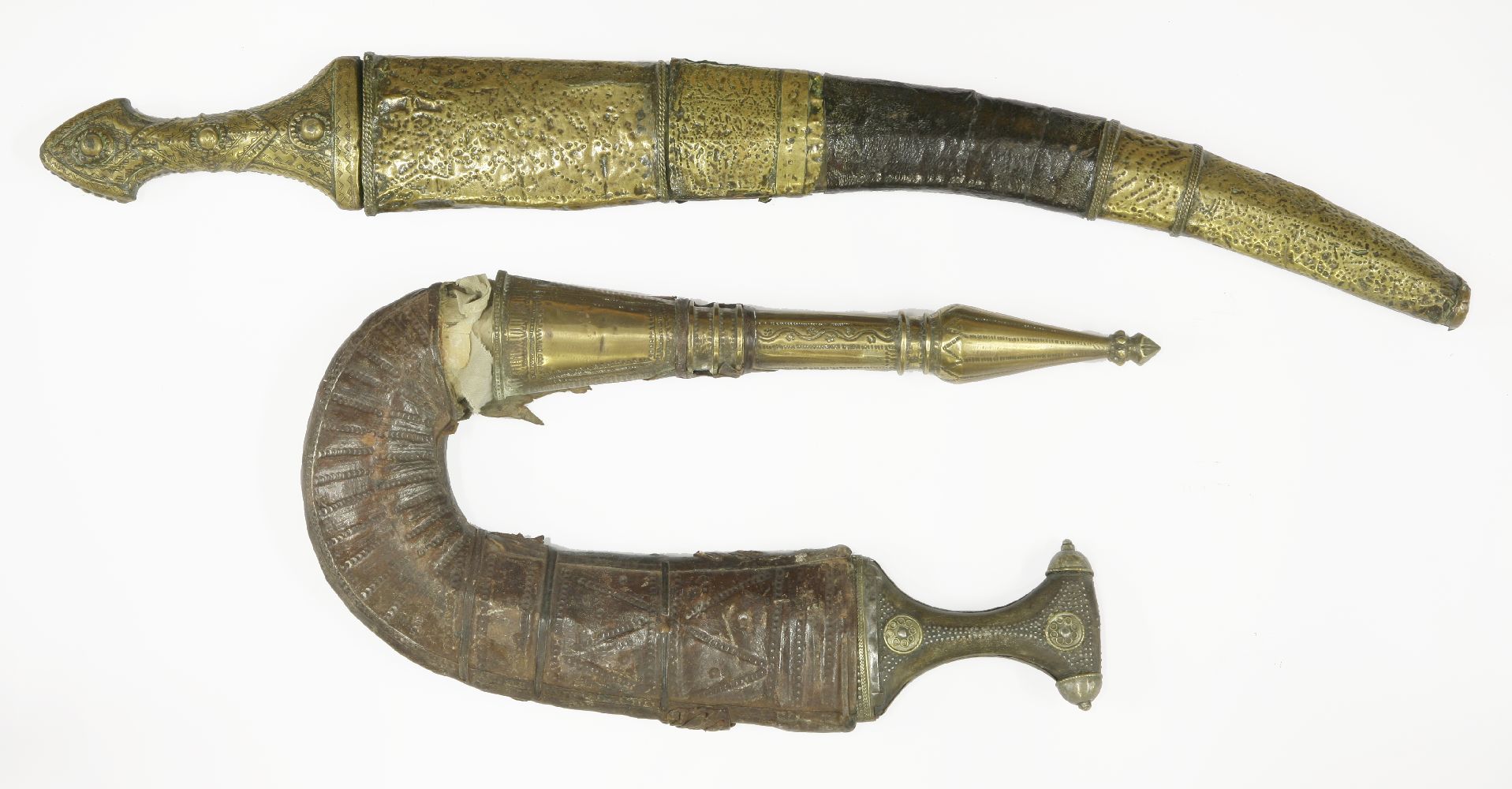 A janbiya, with a metal inset handle and ornate brass and leather sheath, andanother, with an ornate