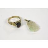 A 9ct gold single stone garnet ring, claw set to bark textured shoulders, and a carved jade