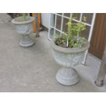 A pair of reconstituted stone urns, moulded lion ring handles to either side on circular spreading