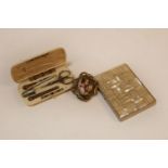 An early 20th century ivory cased sewing set, a cigarette case, and an enamelled swivel brooch