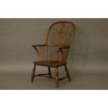 A 19th century elm Windsor armchair, with wheel back above solid seat on stretched turned supports