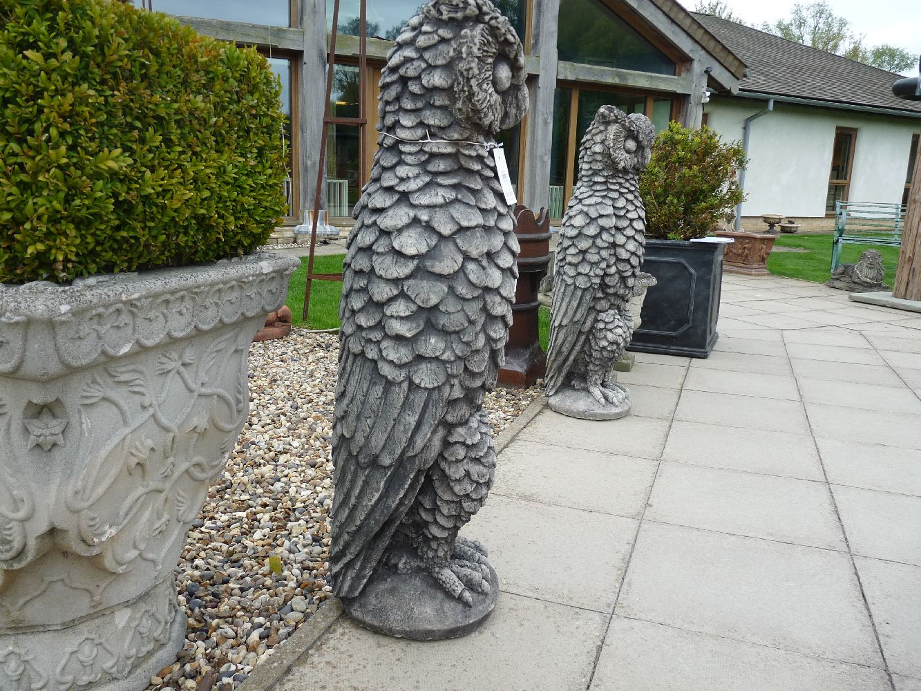 A pair of very large cast stone mythical owls, 37cm wide x 30.5cm deep x 104cm high