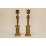 A pair of 19th century brass candlesticks, in the form of a boy holding an urn, standing upon a