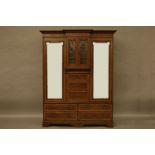 An Edwardian mahogany inlaid breakfront wardrobe, centred with a velvet lined and glazed fronted