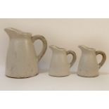 Three graduated white glazed jugs, 21.5 to 34cm