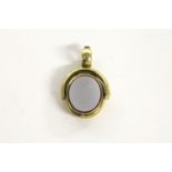 A rolled gold oval hardstone swivel hinged locket/seal, with engraved decoration