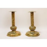 A pair of brass candlesticks, with embossed flowers, spiral moulded columns, on loaded dome bases,