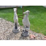 A pair of cast stone garden sculptures of whippets, seated on octagonal bases, 80cm high