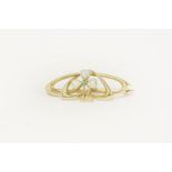 An Art Nouveau gold brooch, set with a demantoid garnet and opal trifoil shamrock, marked 15ct, in a