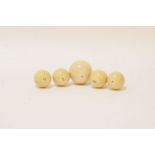 Five 19th century turned ivory balls, four 3.5cm in diameter, and one 5cm diameter