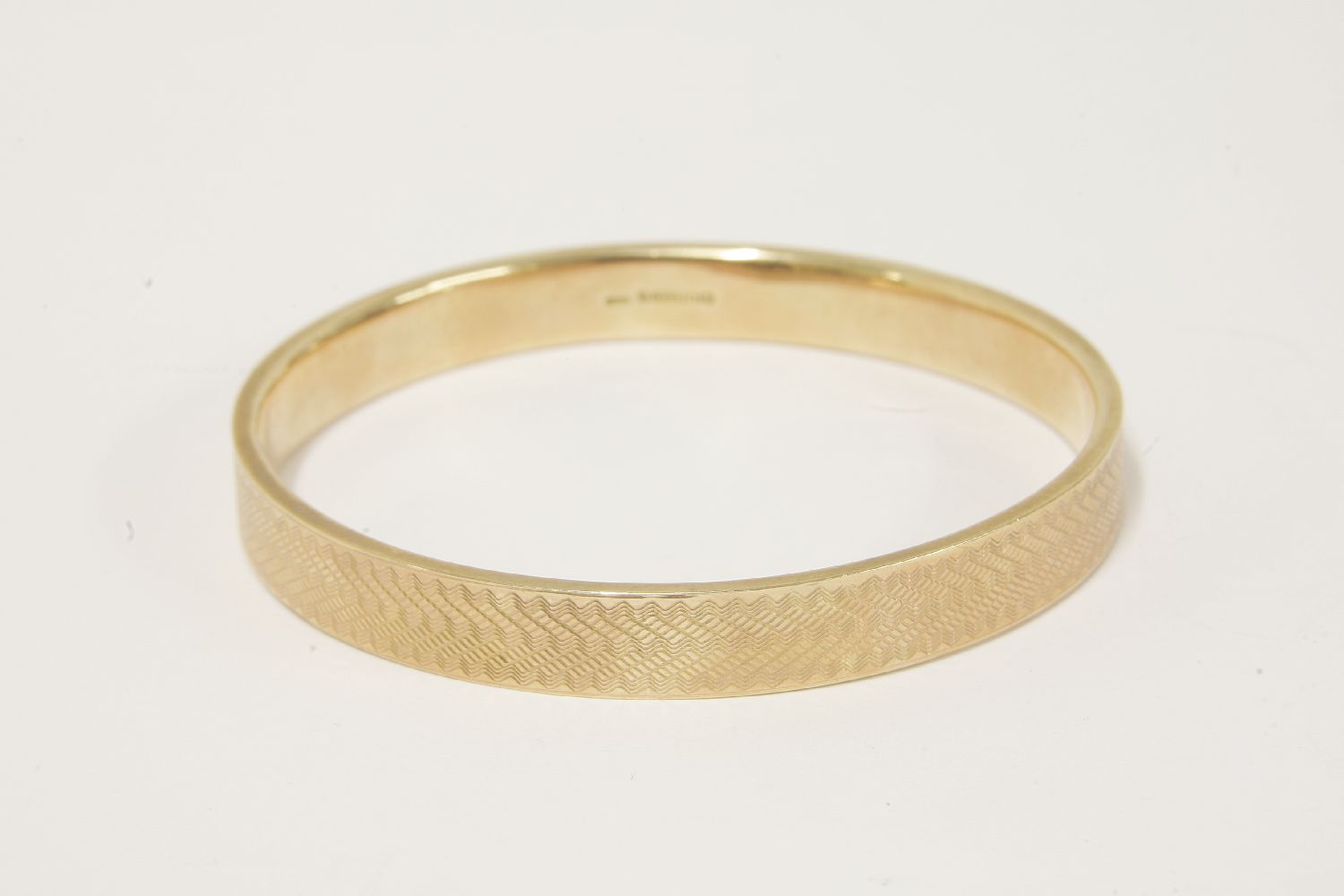 A 9ct gold slave bangle, with engine turned decoration, dated 1921,16.10g