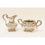 An early 19th century silver milk jug, and sugar bowl, the bodies with leaf moulded and flower