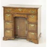 A George II walnut kneehole desk, the strung and crossbanded top over one long drawer and seven