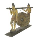 A carved wood and painted dinner gong,20th century, modelled as two oriental men holding the pole