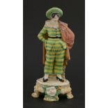 A Cozzi Italian porcelain figure, 19th century, wearing a striped costume, standing on circular