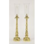 A pair of gilt-bronze table lights, each with ornately case foliate stems on weighted quatraform