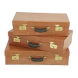 A set of three graduated tan leather suitcases,labelled 'Tanner Krolle', with black canvas covers,
