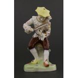 A Dresden figure,20th century, of a seated jester figure ‘playing a cat’, mounted on a triangular