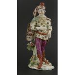 A Derby figure of David Garrick,wearing an elaborate tunic and green cloak, standing on a