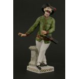 A Meissen figure,of a moustached gentleman wearing a green jacket and tricorn hat, with slapstick,
