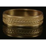 A Victorian gold flat section hinged Etruscan-style bangle, c.1870,17mm wide. Decoration to the