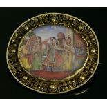 An Indian, gold, painted miniature brooch,depicting musicians and couples watching a lady dancing,