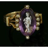 An Edwardian paste and split pearl ring,with an oval purple paste, with hand painted enamel putto,