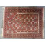 A Persian Belouch prayer rug, the red fields with temple filled centre within a triple boarder