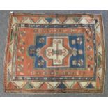 A hand knotted Caucasian rug, the blue and red fields with pendant centre within a triple boarder (