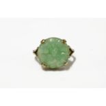 A carved jade plaque ring, a circular carved jade plaque of a moth design, claw set to a plain