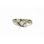 A three stone diamond crossover ring with diamond set shoulders, stamped 18ct and plat