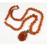 A Chinese single row graduated agate bead necklace, with green glass and carved agate pendant, in