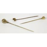 Three gold stick pins comprising a ball finial example, a drop finial stick pin with engraved