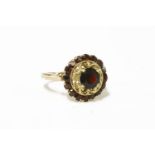 An Italian gold garnet cluster ring, single round cut garnet, claw set to pierced openwork to a