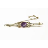 An Edwardian gold single stone round cut amethyst bar brooch, flanked with seed pearls4.37g