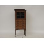 An Edwardian inlaid mahogany music cabinet, with glazed door over four drawers