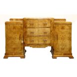 An Art Deco walnut sideboard, the raised central section fitted with three drawers, flanked with
